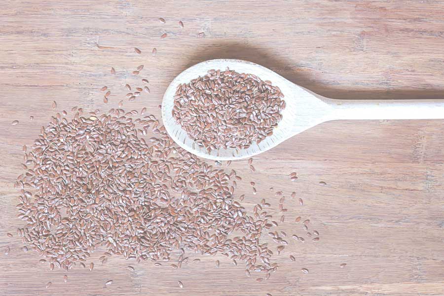 Flax seeds in a wooden spoon - Health supplements and vitamins suitable for vegan - Link to Highland Health online shop - products category Food and Drink